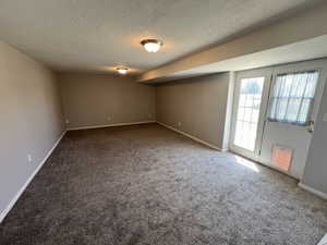 Spare room featuring a textured ceiling, carpet floors, and baseboards