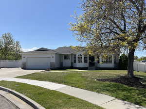 Ranch-style house featuring driveway, a garage, fence, and a front yard