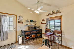 Interior space featuring lofted ceiling, wood finished floors, a toaster, ceiling fan, and baseboards
