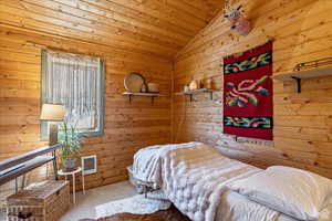Bedroom with carpet, visible vents, wood ceiling, wooden walls, and vaulted ceiling
