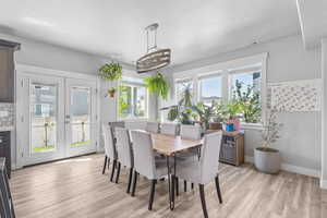 Dining space with french doors, and light wood-style flooring
