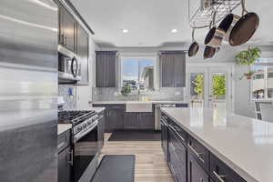 Kitchen with stainless steel finishes, light wood-style floors, tasteful backsplash, and recessed lighting