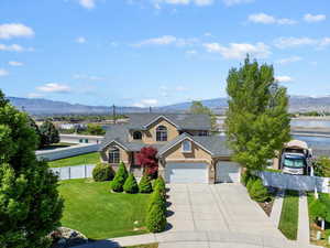 Traditional home with a front lawn, a mountain view, fence, and concrete driveway