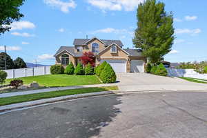 Traditional-style house featuring a garage, a front lawn, fence, stucco siding, and concrete driveway