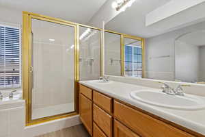 Primary bathroom with a sink, a stall shower, and double vanity and a walk in closet