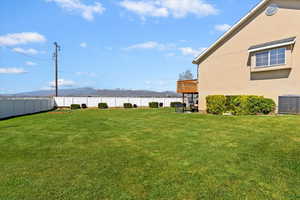 View of yard featuring cooling unit, a mountain view, and a fenced backyard