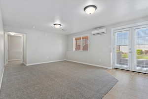 Walkout entry into basement family room featuring baseboards, a wealth of natural light, and a wall mounted air conditioner