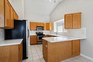 Kitchen featuring a peninsula, high vaulted ceiling, appliances with stainless steel finishes, and tasteful backsplash