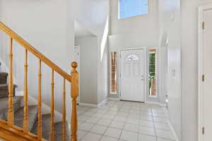 Foyer entrance featuring stairs, arched walkways, baseboards, and light tile patterned floors