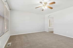 Primary bedroom with visible vents, arched walkways, carpet, and baseboards