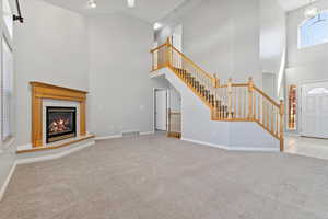 Unfurnished living room with carpet floors, baseboards, a towering ceiling, and visible vents