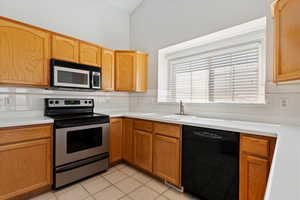 Kitchen with backsplash, stainless steel range with electric cooktop, a sink, black dishwasher, and light tile patterned flooring