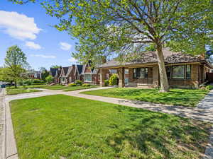 View of front of home featuring a front lawn, concrete driveway, brick siding, covered porch, and an attached carport
