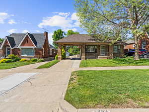 View of front of home featuring driveway, brick siding, an attached carport, a front lawn, and covered porch