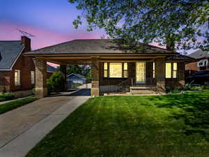 View of front of home featuring concrete driveway, brick siding, a carport, and a front lawn