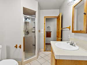 Bathroom featuring a shower stall, toilet, tile patterned floors, and baseboards