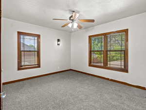 Carpeted empty room featuring baseboards and a ceiling fan