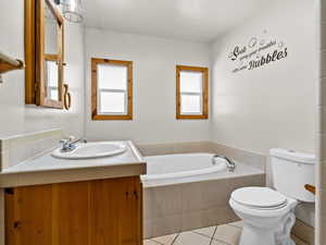Bathroom with toilet, tile patterned flooring, a bath, and vanity