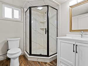 Full bath with wood finished floors, a marble finish shower, toilet, and vanity