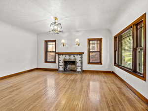 Unfurnished living room with light wood-style flooring, plenty of natural light, baseboards, and a textured ceiling