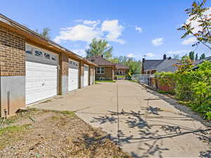 Garage with concrete driveway, fence, and a residential view