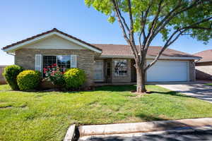 Ranch-style house featuring an attached garage, brick siding, concrete driveway, a tiled roof, and a front lawn