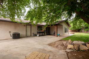 Rear view of property with a patio, stucco siding, fence, a lawn, and central AC unit