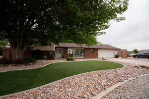 View of front facade with concrete driveway, brick siding, a front yard, and a garage