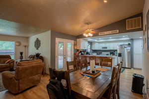 Dining area featuring light wood-type flooring, ceiling fan, lofted ceiling, and visible vents