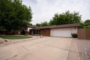 Tri-level home with fence, a garage, concrete driveway, and brick siding