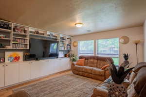 Living room featuring light wood finished floors, visible vents, and a textured ceiling