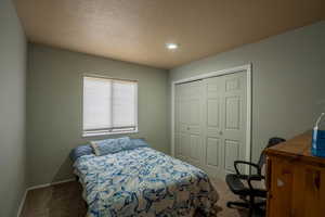 Bedroom with baseboards, a textured ceiling, a closet, and carpet