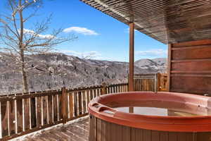 Deck featuring a hot tub and a mountain view