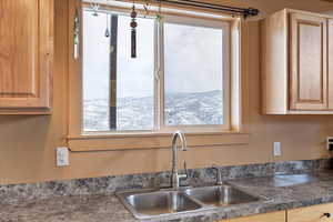 Kitchen with dark countertops, light brown cabinetry, and a sink