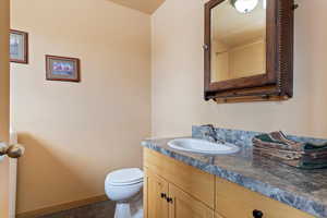Half bathroom featuring toilet, baseboards, and vanity