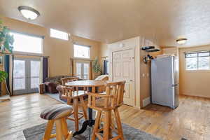 Dining space featuring a textured ceiling, visible vents, french doors, and light wood-style flooring