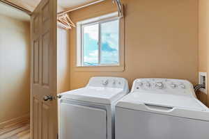 Washroom featuring independent washer and dryer, light wood-style floors, baseboards, and laundry area