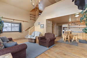 Living room featuring a towering ceiling, light wood-type flooring, visible vents, stairway, and baseboards