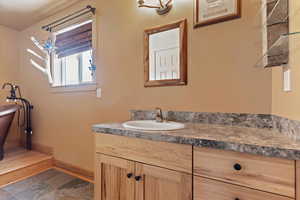 Bathroom featuring baseboards, vanity, and a freestanding tub
