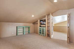 Additional living space with lofted ceiling, a textured ceiling, and carpet floors