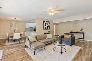 Living area with visible vents, light wood-style flooring, baseboards, and ceiling fan