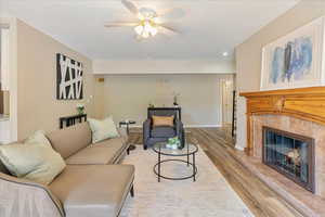 Living area featuring wood finished floors, recessed lighting, a fireplace, ceiling fan, and baseboards