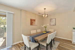 Dining area with wood finished floors, baseboards, and a notable chandelier