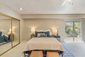 Carpeted bedroom with a ceiling fan, a closet, a textured ceiling, and access to exterior