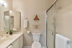 Bathroom with a shower stall, baseboards, vanity, and toilet