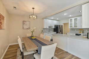 Dining space featuring wood finished floors, baseboards, visible vents, recessed lighting, and a notable chandelier