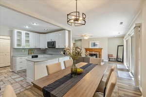 Kitchen with stainless steel microwave, a peninsula, a fireplace, light countertops, and glass insert cabinets