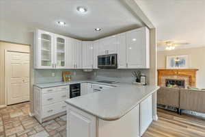 Kitchen featuring white cabinets, black electric cooktop, glass insert cabinets, and stainless steel microwave