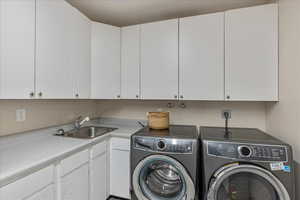 Laundry room with cabinet space, washing machine and clothes dryer, and a sink