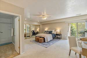 Bedroom with a textured ceiling, carpet, visible vents, baseboards, and access to exterior